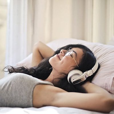 Dm-Harmonics-folgen von zu wenig schlaf-Frau liegt mit Kopfhörern im Bett